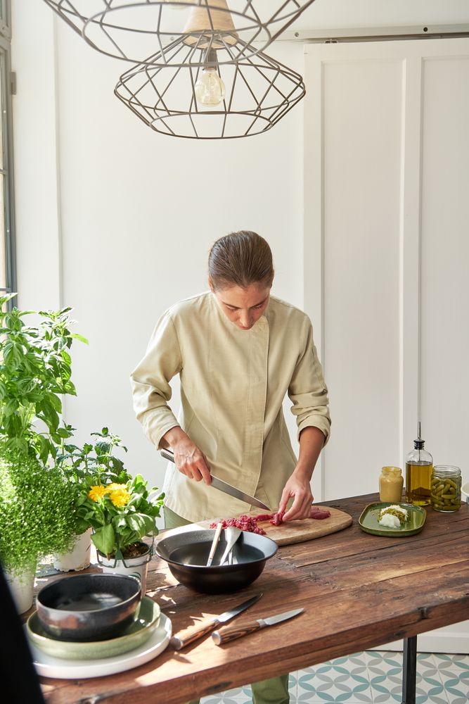 Serious woman cooking steak tartare at home