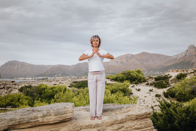 Barefoot woman meditating on stone