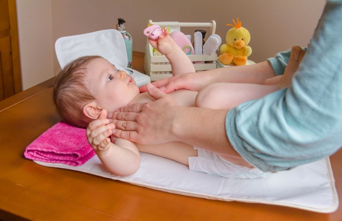 Mother applying cream to baby while changing diaper