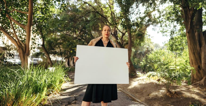 Fashionable woman looking at the camera while holding up a blank placard