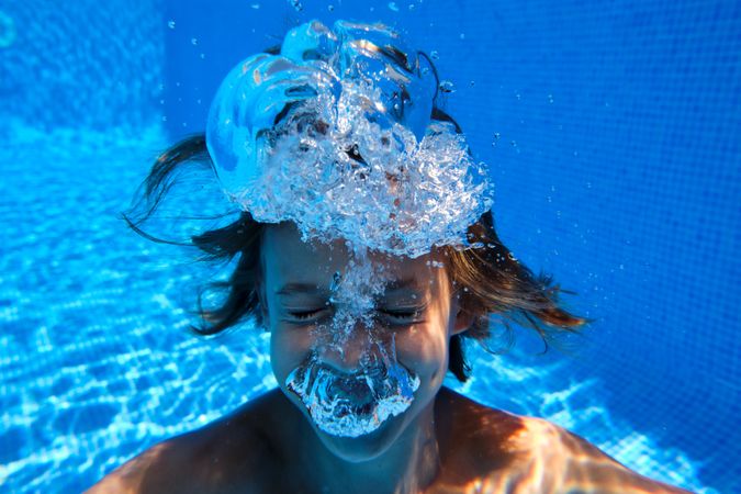Funny preteen boy swimming in pool