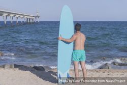 Male surfer holding his surfboard looking out to the view 47Y8O0