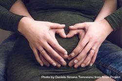 Heart shaped hands over a belly of pregnancy 0LOgDb