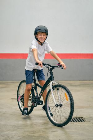 Smiling boy on modern bicycle on parking lot