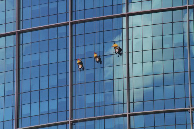Three people cleaning windows of skyscraper