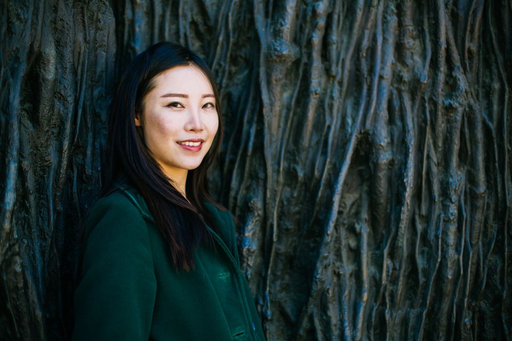 Cheerful Asian woman leaning on rough wall