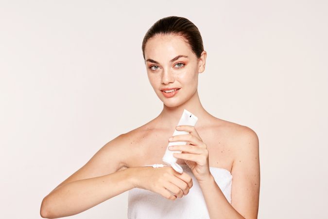 Appealing female applying moisturizing cream on hands