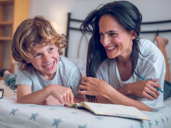Laughing mother helping preteen son doing homework