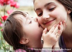 Young girl giving big sister a kiss on cheek 4j6mJ4