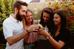 Group of cheerful friends clinking glasses at party