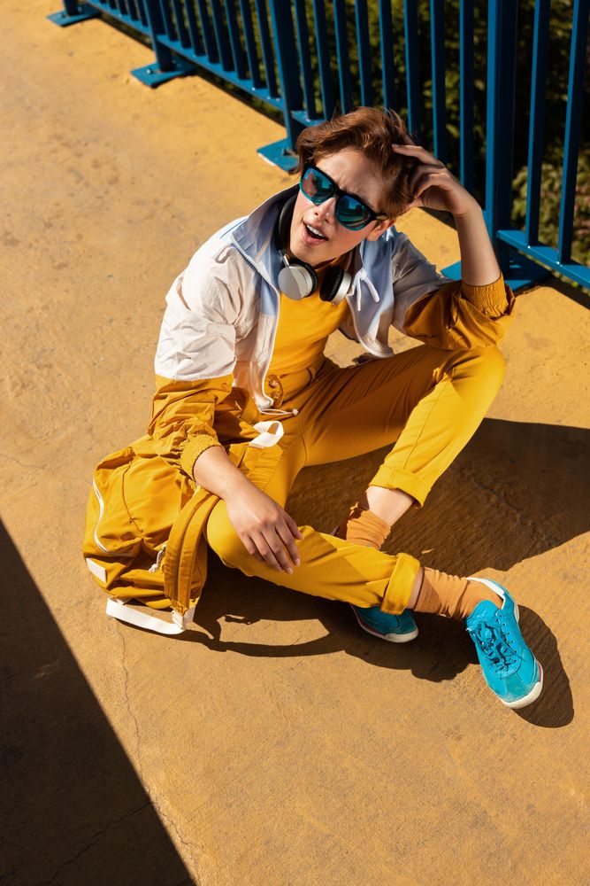 Stylish young woman in vibrant clothes enjoying music on street