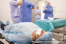 Mature woman in hair net and facemask lying down pre-surgery 5XvjQb