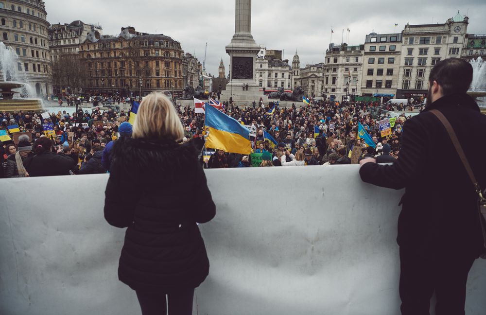 London, England, United Kingdom - March 5 2022: Two people holding banner looking out at protest