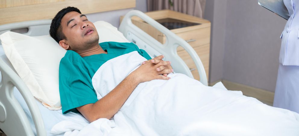 Sick man lying in hospital bed sleeping