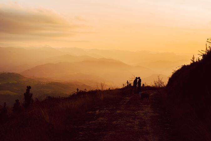Men hugging near dog on road on hill