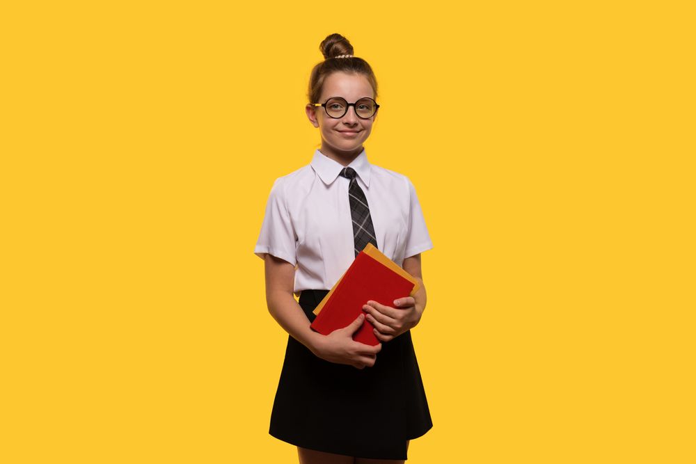 Teen girl holding books, wearing glasses and school uniform