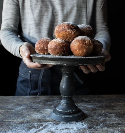 Person near baked cakes on stand on table