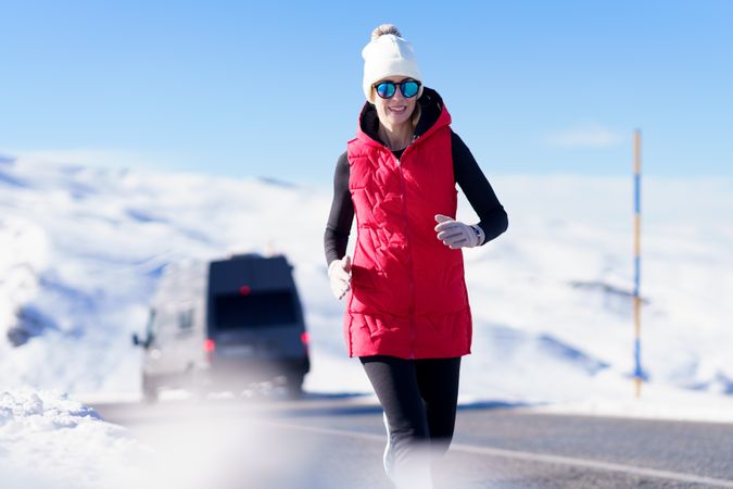 Woman in snow wear jogging on mountain road