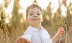 Kid in field playing with spikes at summer sunset
