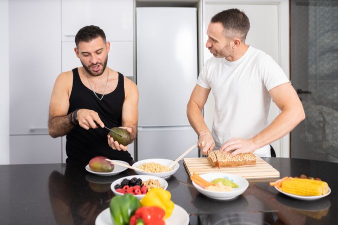 Happy male couple preparing vegetables and bread for lunch