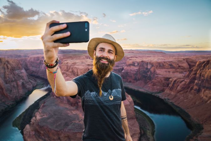 Cheerful traveler taking selfie near canyon