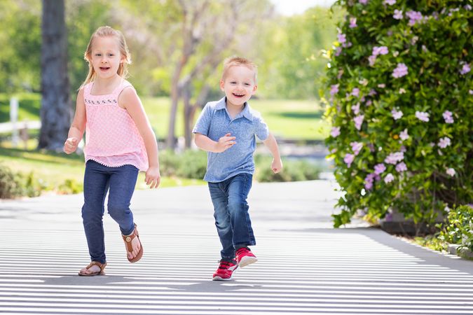 Young Sister and Brother Having Fun Running At The Park