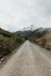 Countryside road on wonderful valley with trees and high hills in cloudy weather