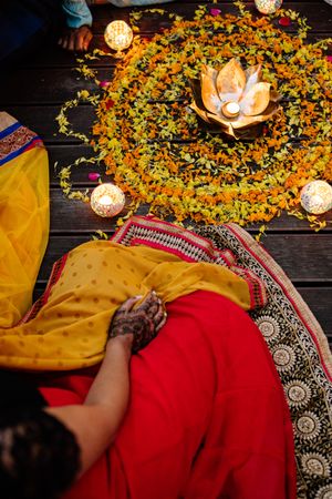 Top view of Indian woman sitting beside Rangoli with candles