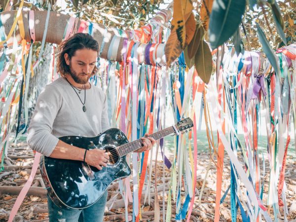 Man playing guitar under decorated tree