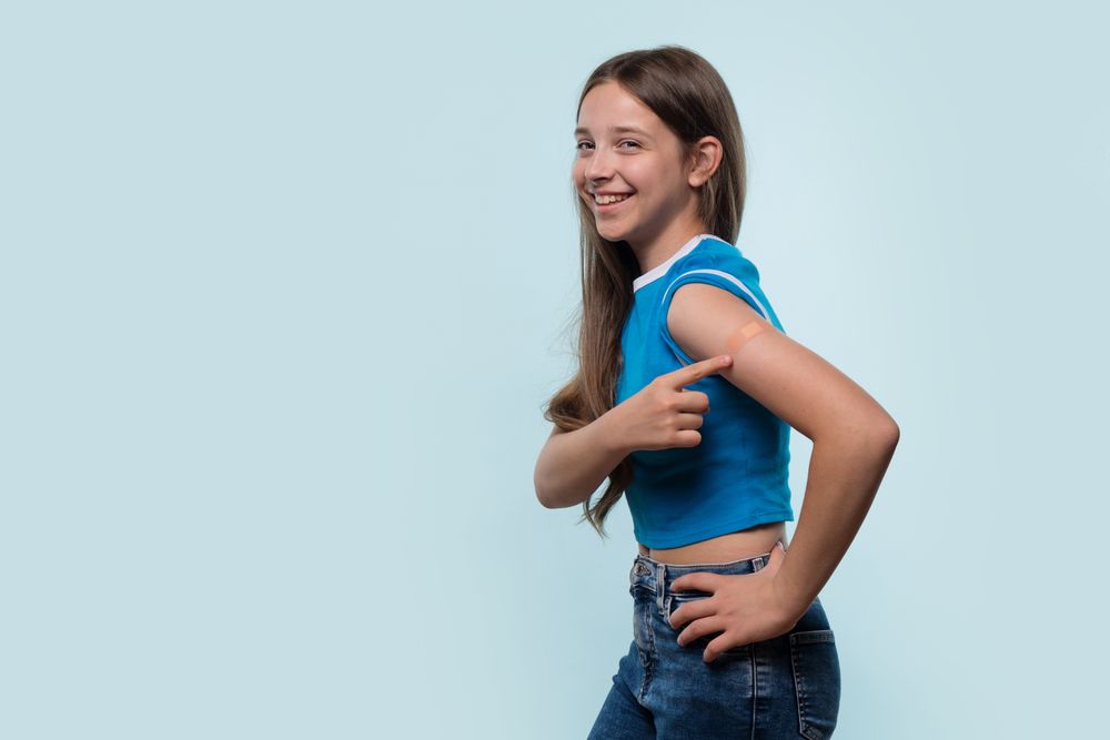 Young girl pointing at bandage on arm after vaccination