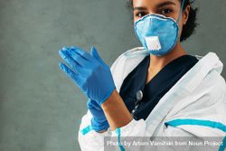 Black woman in facemask putting on protective gloves 48kXv5