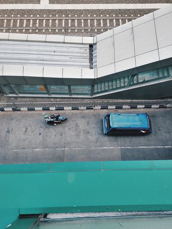 High-Angle View of Urban Scene: Motorbike, Van, Railway Tracks, and Modern Architecture