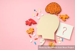 Paper cut out of side view of head with medications and puzzle pieces on pink background, copy space 4ADlY5
