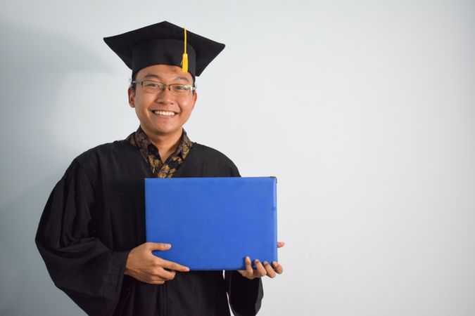 Smiling male graduate in studio shoot holding certificate