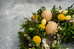Easter card concept with fresh wreath with decorative eggs and feathers