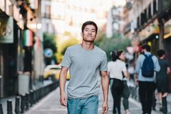 Confident Asian man walking along city street