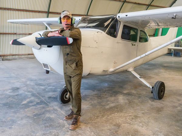 Confident pilot beside retro plane in hangar