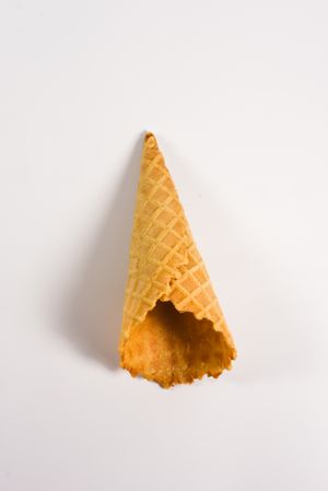 Top view of empty waffle cone lying on plain table, vertical