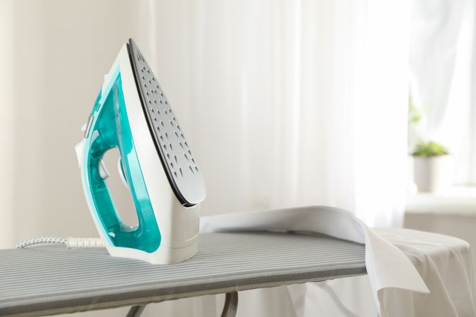 Iron and shirt on ironing board, space for text