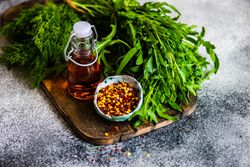 Close up of chili flakes and oil with herbs on bread board