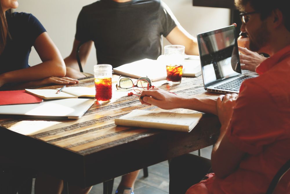 Group of young people sitting at table with notebooks and laptop