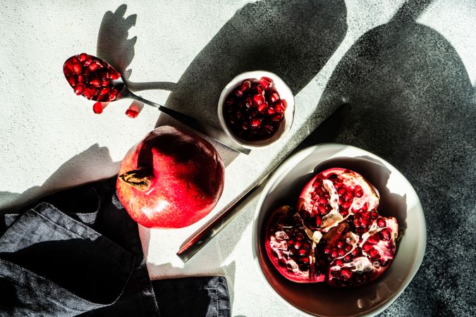 Pomegranate in bowl with side of seeds and spoon