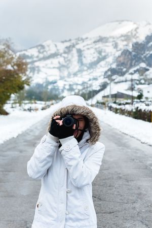 Content woman taking picture in snowy mountains
