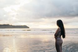 Young woman watching sunset standing on the beach