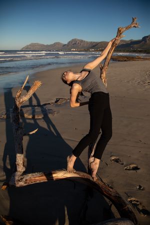Young woman dancing and posing near water on shore