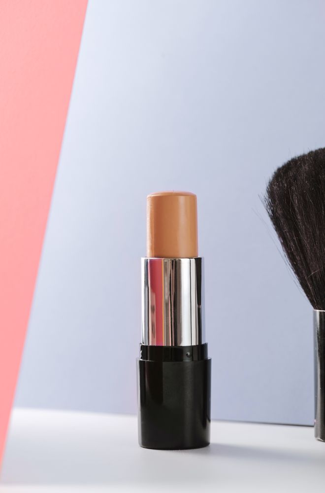 Concealer stick and make up brush on modern background