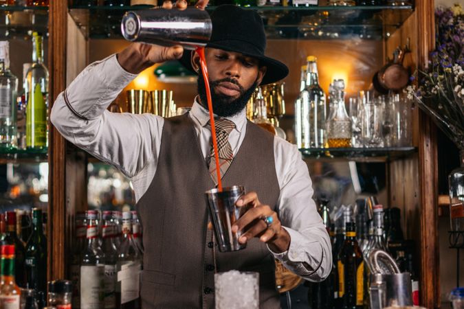 Stylish Black bartender preparing a cocktail in a traditional cocktail bar