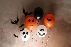 Different balloons on brown background. Halloween concept, space for text