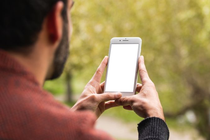 Anonymous man browsing on mobile phone on terrace