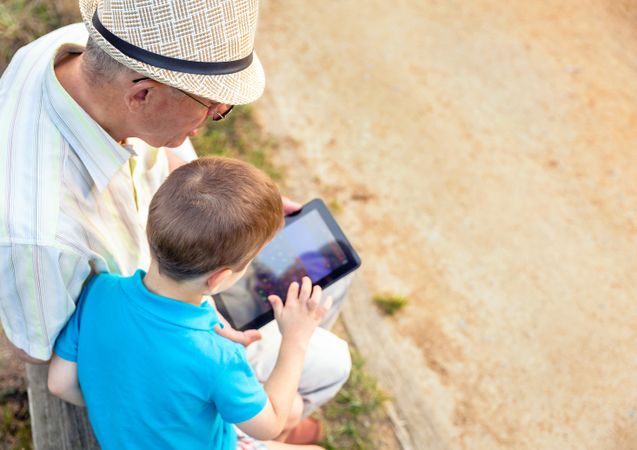 Looking down at grandchild and grandfather using a tablet outdoors
